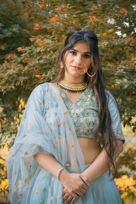 the woman is wearing a light blue blouse and earrings