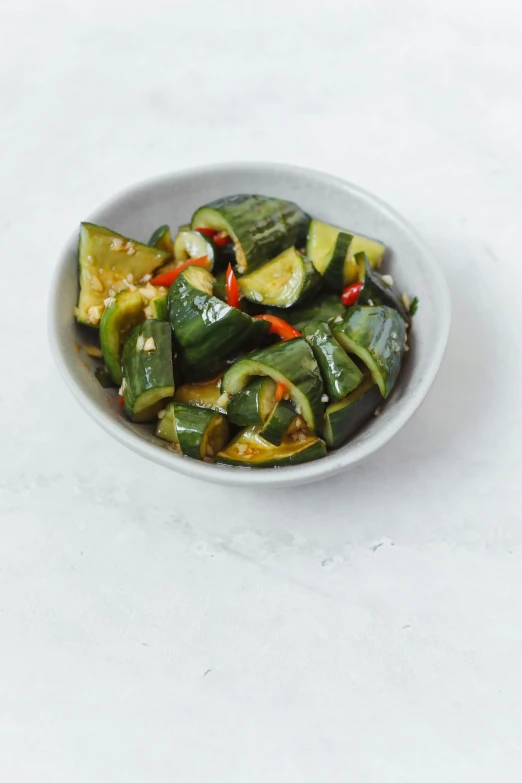 a bowl of fried green vegetables on a white table