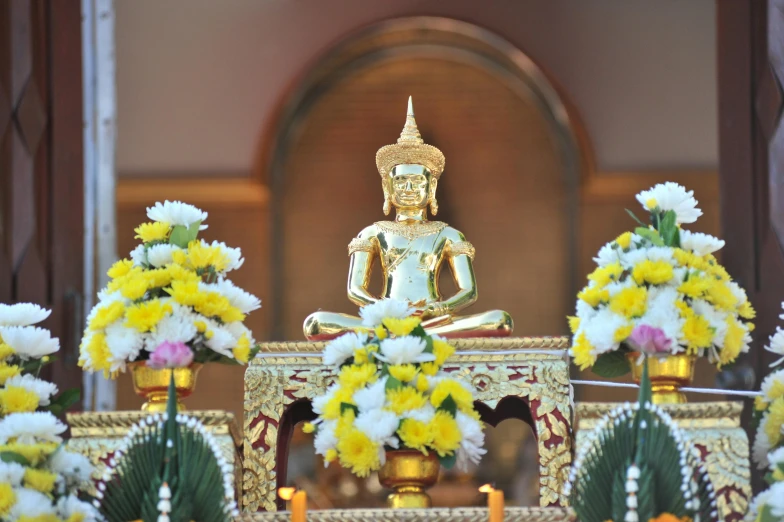 flowers around a buddha statue sitting on the floor