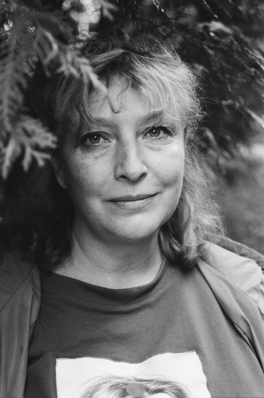 a woman smiles for a portrait in front of some trees