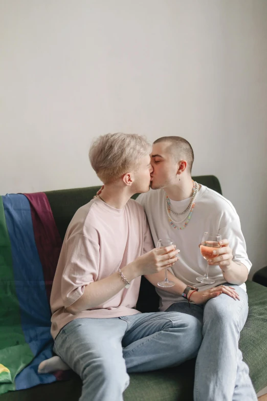 two people sit on a couch, one holding a wine glass