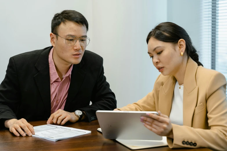 two people sitting at a table looking at a paper