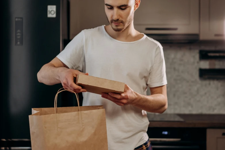 a man with a paper bag and package looking at it