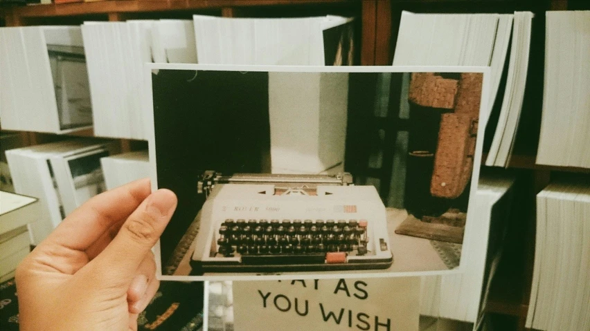 a person is holding up a picture of a typewriter