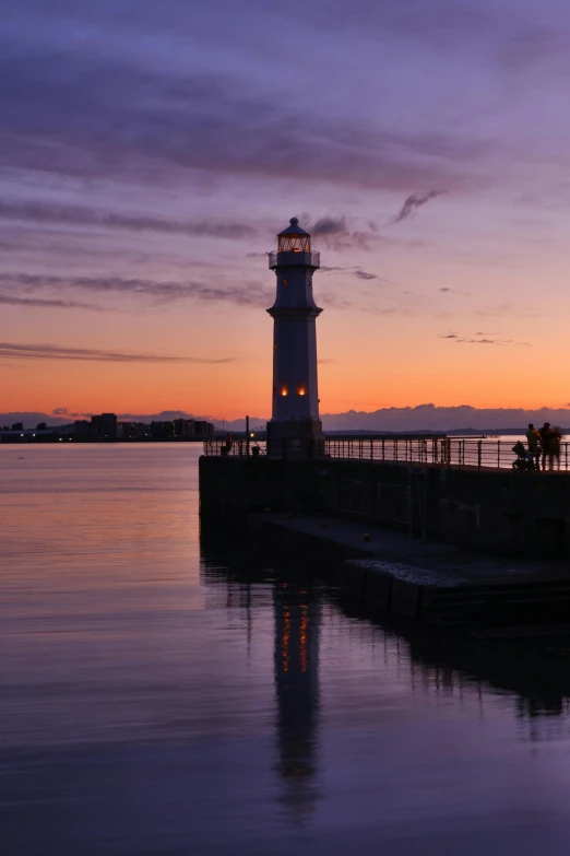 a lighthouse surrounded by the water with the sun setting