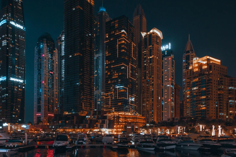 a night scene of boats and buildings in a marina area