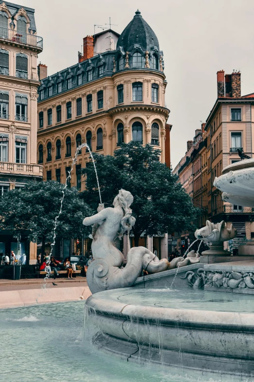 a fountain with two children playing in it next to some buildings
