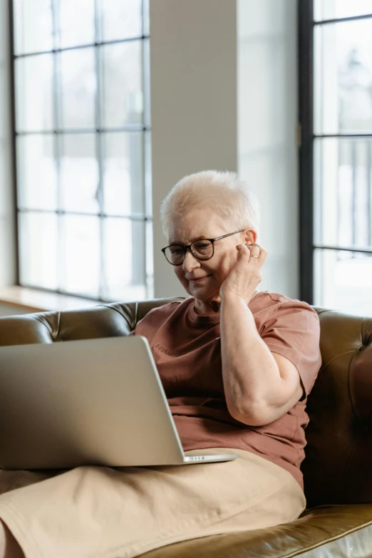 an older man is on his computer sitting on a coach