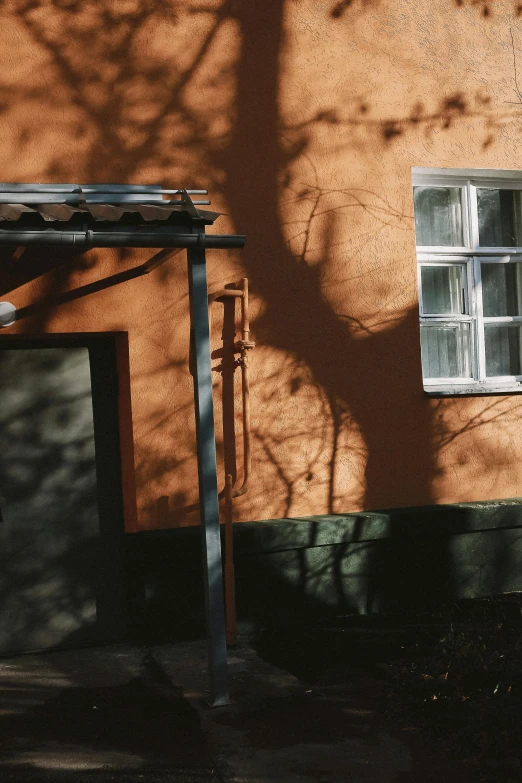 a fire hydrant near a building, with the shadow of a tree on it