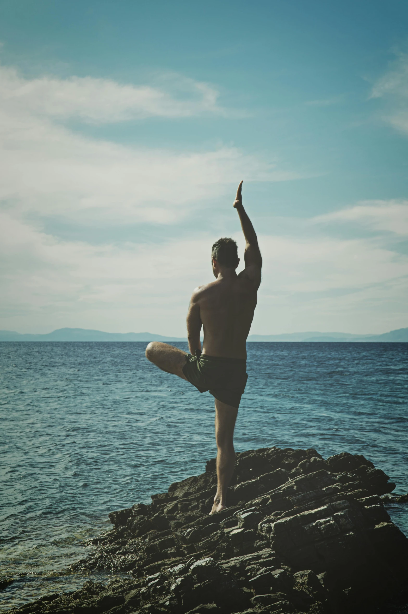 a man standing on top of a rock near the ocean