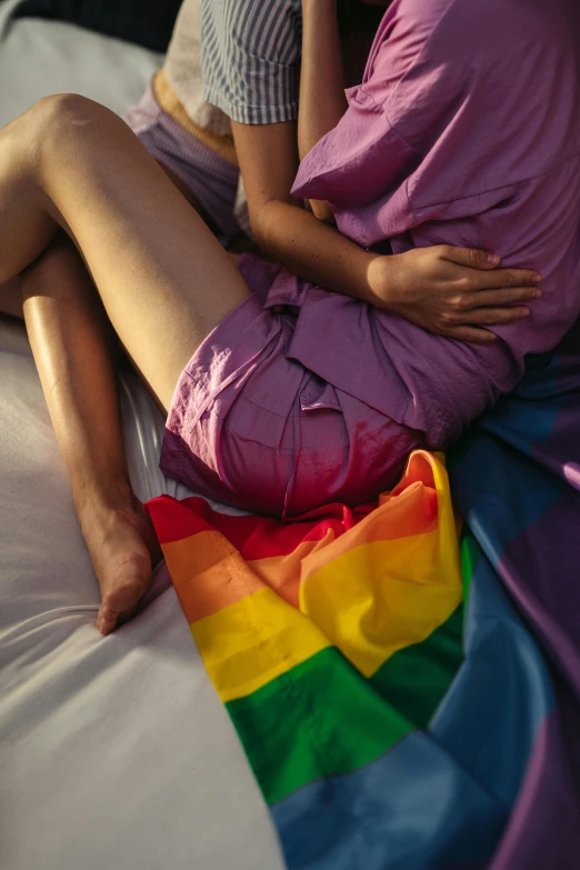 two people sitting on top of a rainbow colored bed