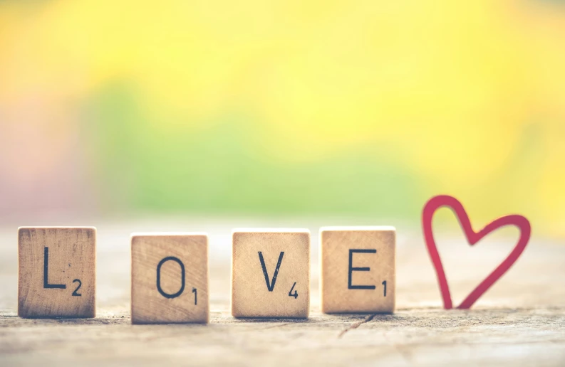 love spelled with wood cubes in front of a heart