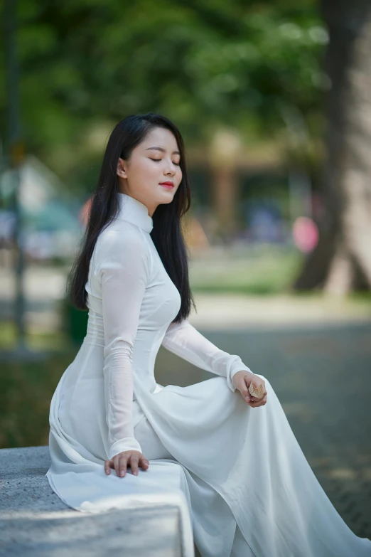 a young woman sitting on the ground wearing a dress