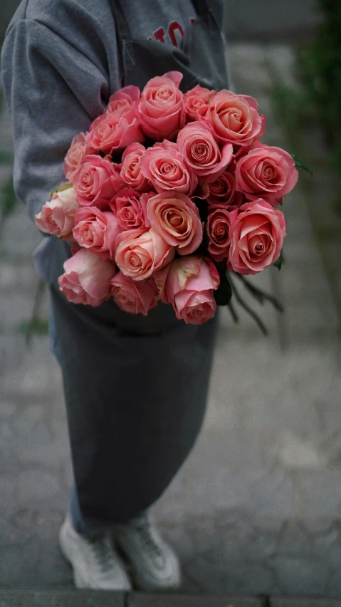someone is holding a bouquet of pink roses