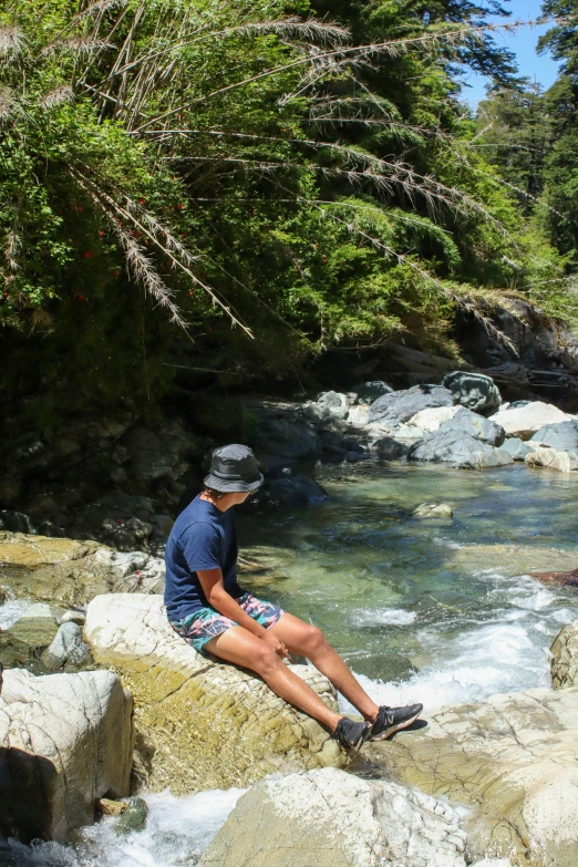 a person sitting on a rock in the river