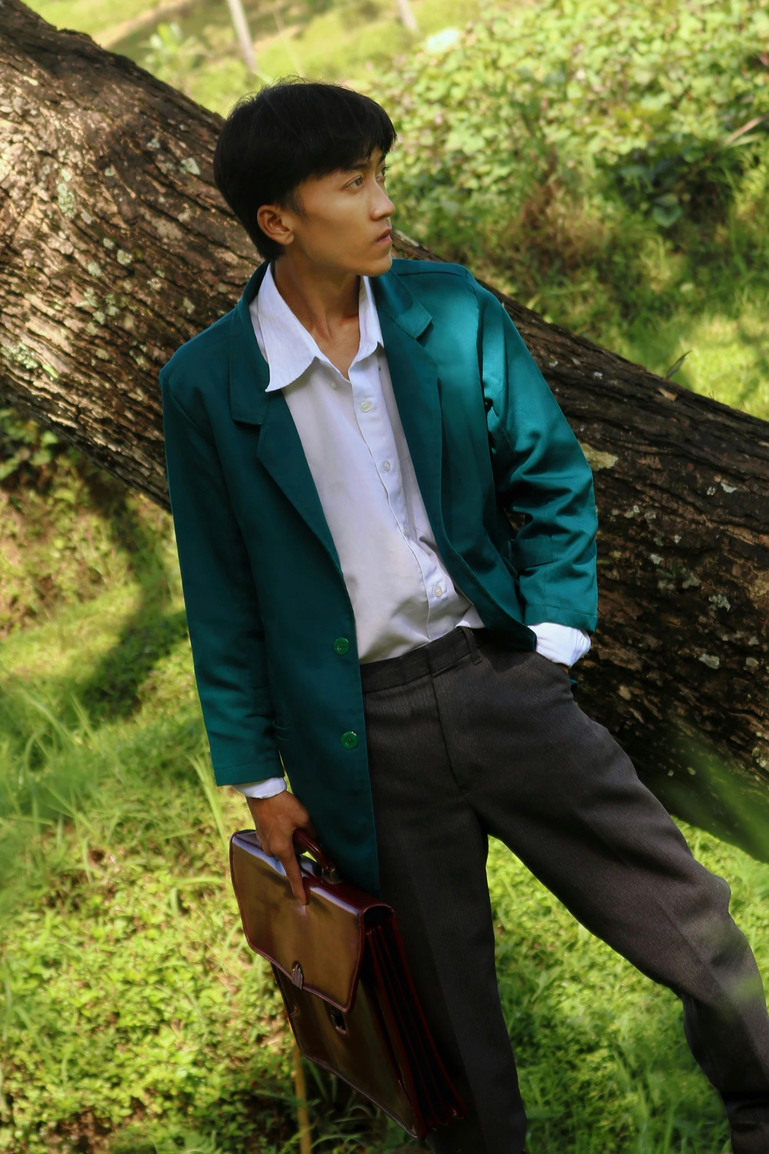 a man standing near a large tree in the grass