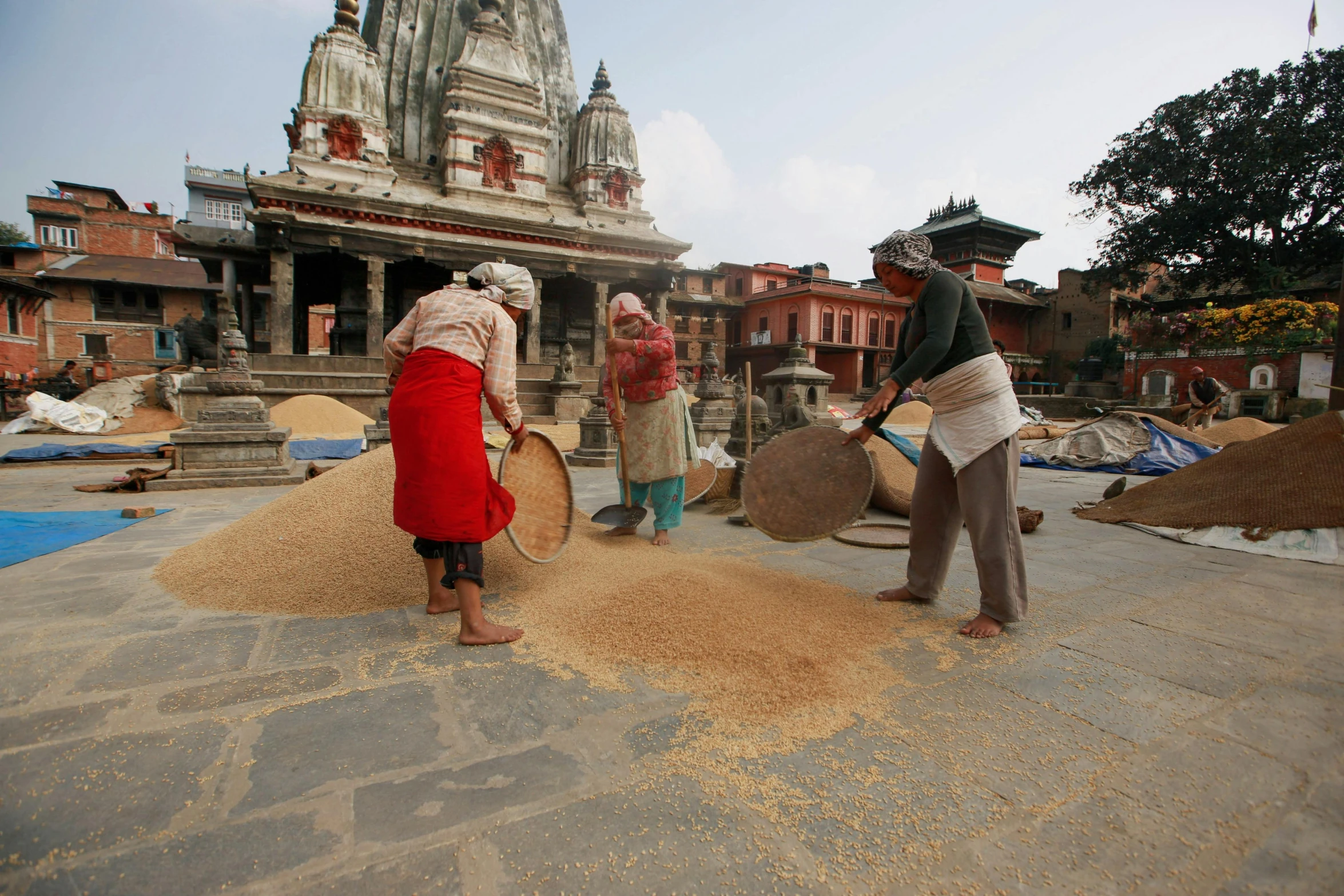 people work on an outdoor sand sculpture in the sand