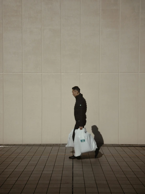 a man walking down a sidewalk with his suitcases