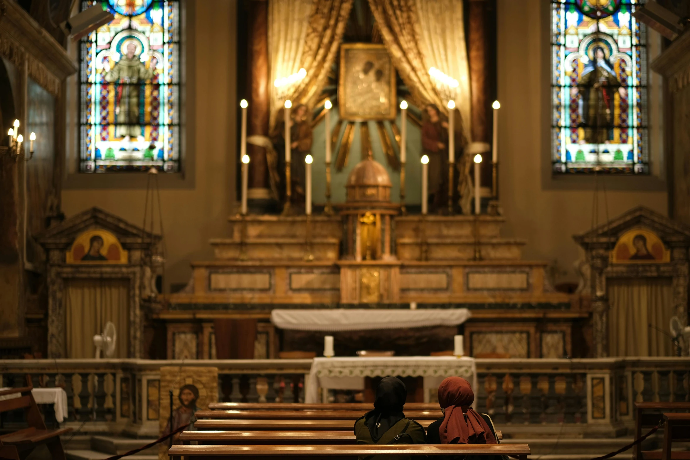 a woman and child sit at the alter of a church