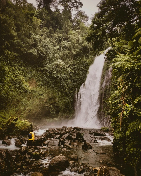 a waterfall and two people standing in a stream