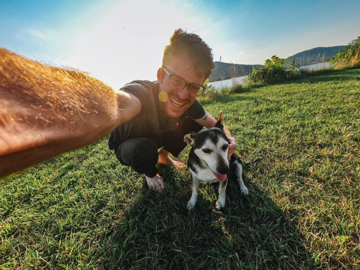 a person in the grass petting a dog