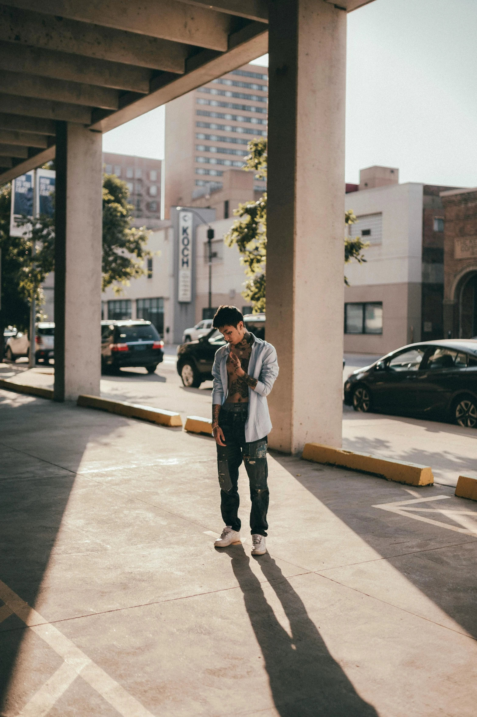 a young man standing in the shade with his phone