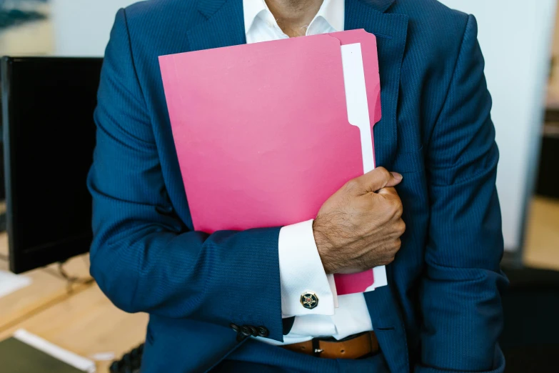 a man in a suit holds a book with both hands