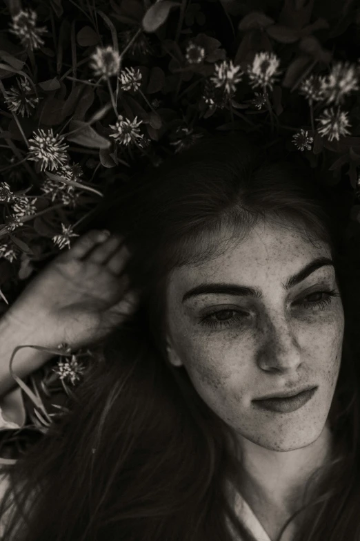 a beautiful woman laying in the grass next to flowers