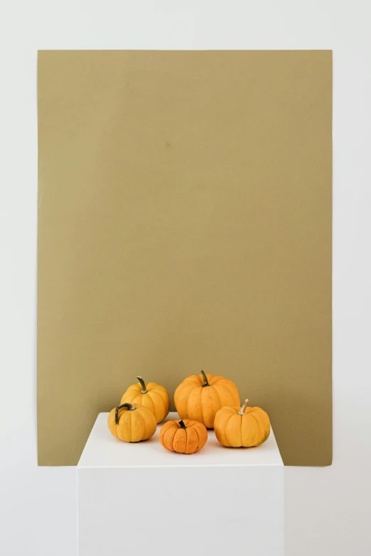 four pumpkins are sitting on a pedestal against a brown wall