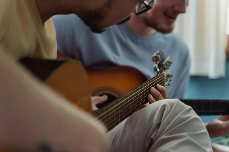 two guys playing music together, one is playing the guitar