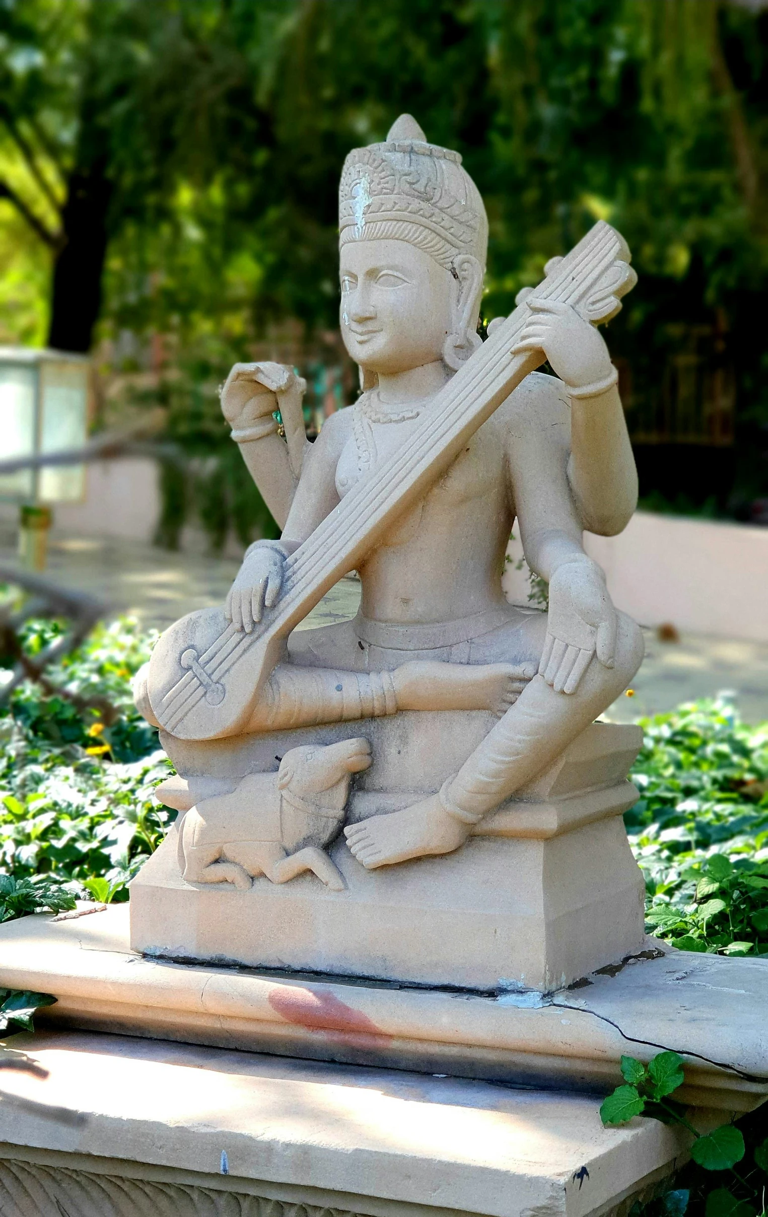 a small statue in the middle of some flowers