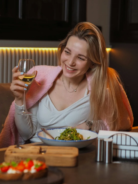 a woman is holding a glass and smiling while she sits down