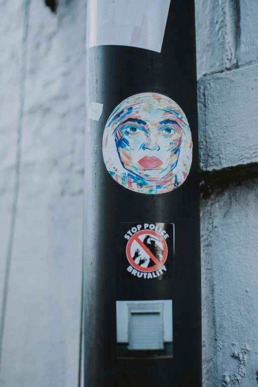 an outdoor toilet stall with stickers depicting a face and other graffiti designs