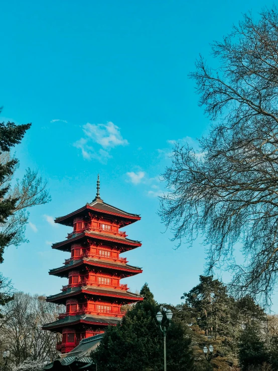 a tall red building next to trees under a blue sky