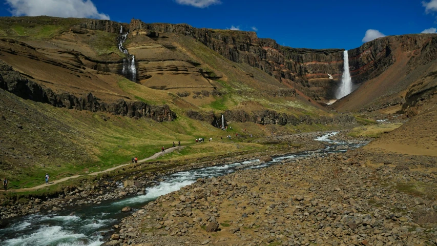 three people riding horses in front of a waterfall