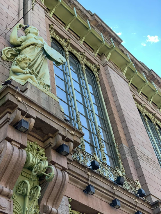 a green and brown statue on the side of a brick building