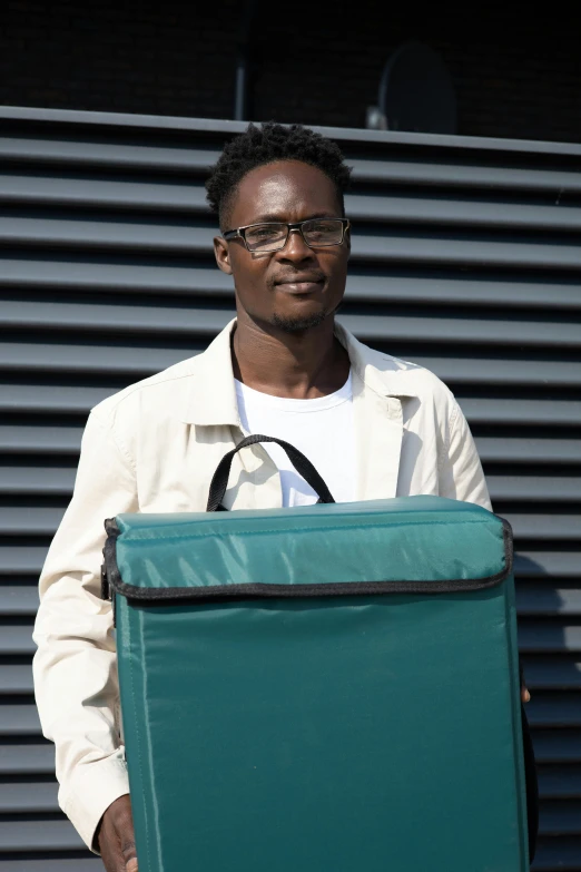 the man is holding a big green suitcase