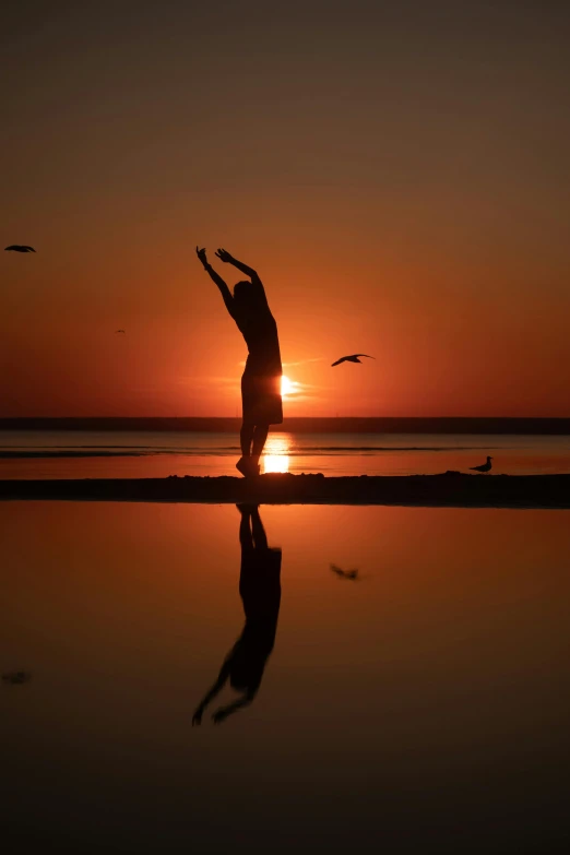 a person standing in front of the sun, arms raised