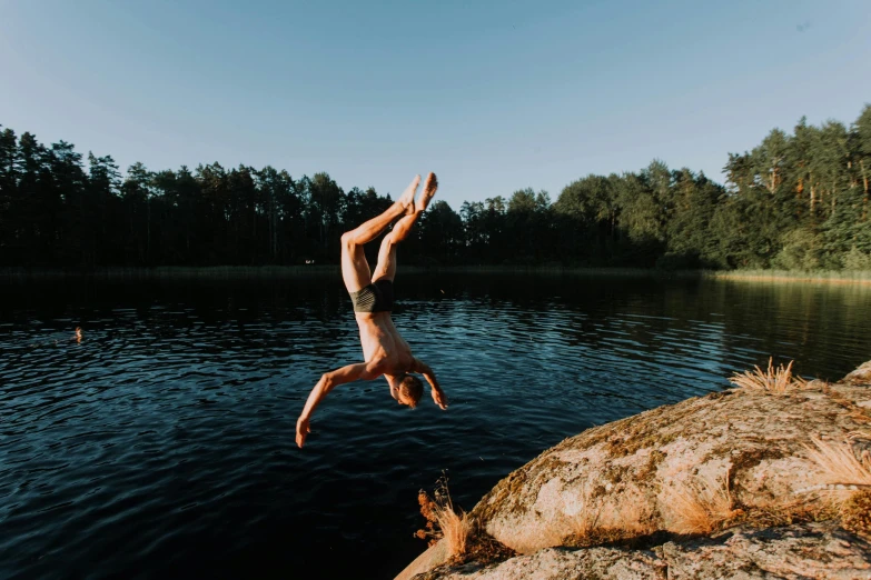 someone doing a hand flip off a cliff in the water