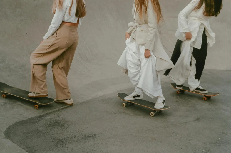 three s riding skateboards in different outfits