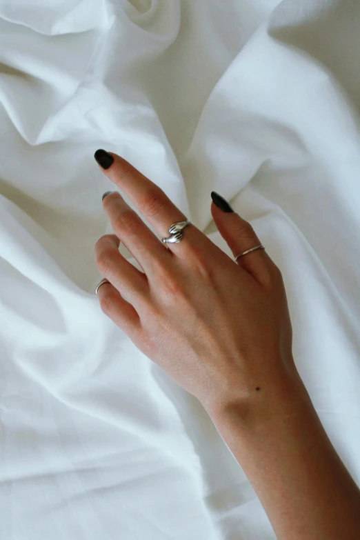 the woman's hands are lying in a bed on a white sheet