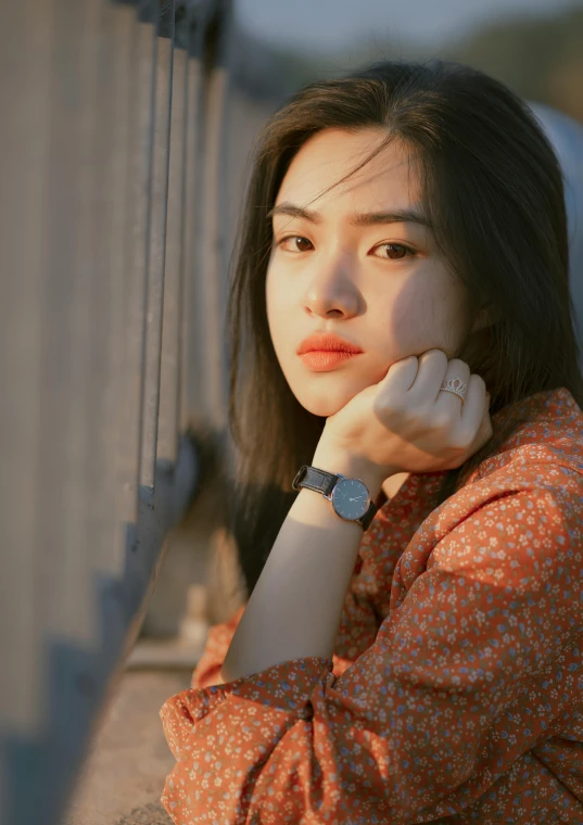 the woman looks off into the distance, with a watch on her hand