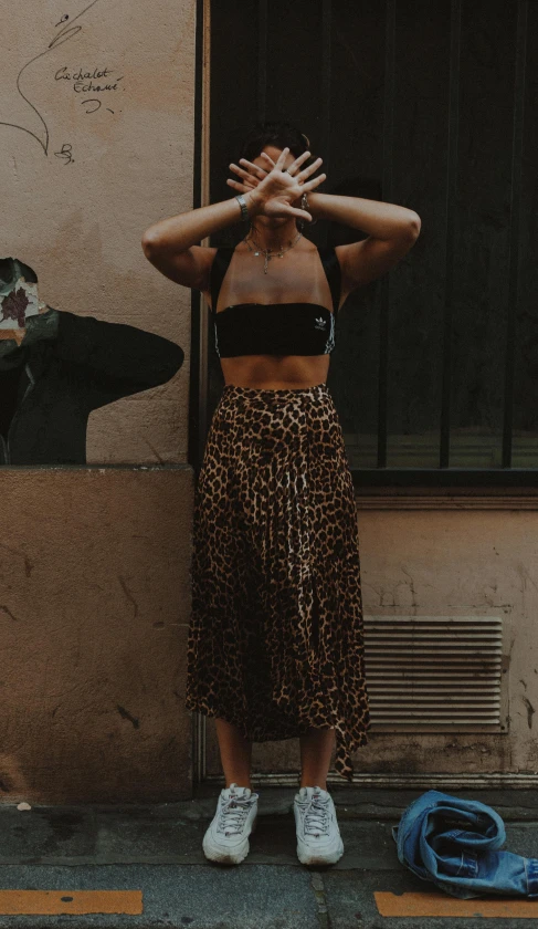 an old woman stands in front of a doorway with her hands above her face and covering her eyes