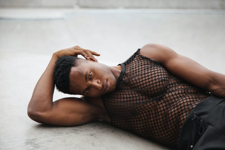 a man in fishnet clothing laying on a floor