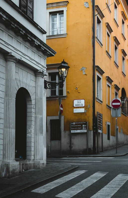 there is a tall yellow building next to a stone wall