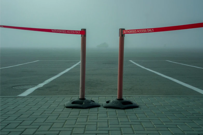 two posts in a concrete parking lot with red tape