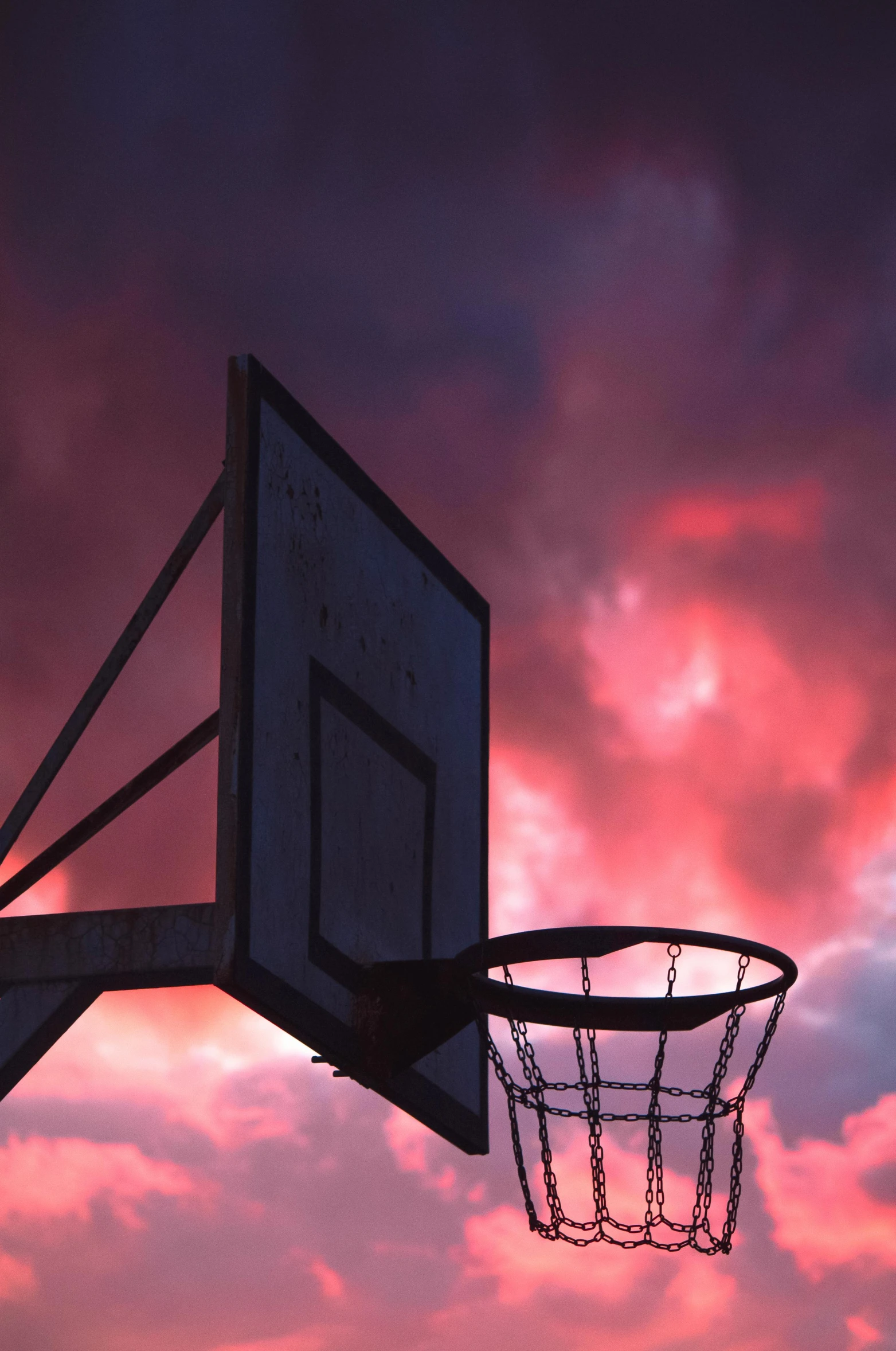 a basketball goal and basket against an orange sunset