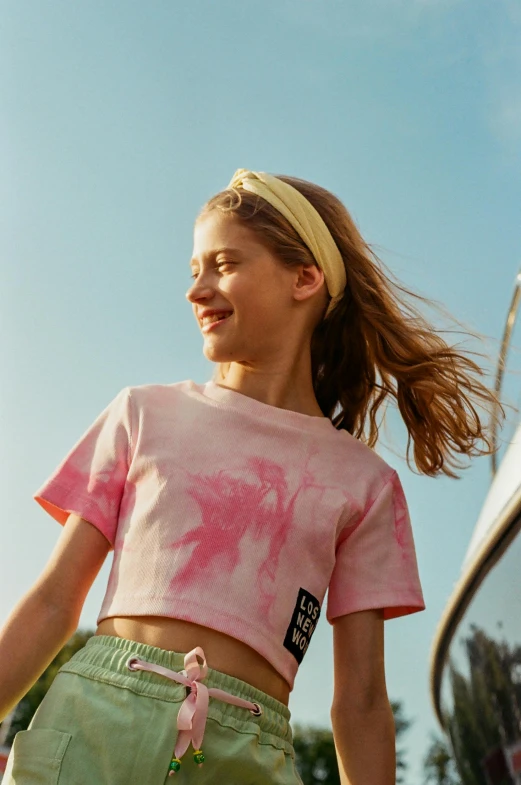 a girl with pink hair wearing a tie dye shirt and green shorts