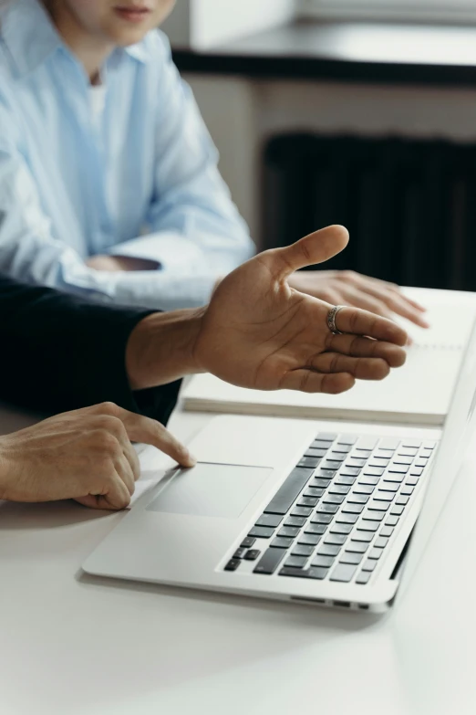 a person pointing out her hand to a laptop