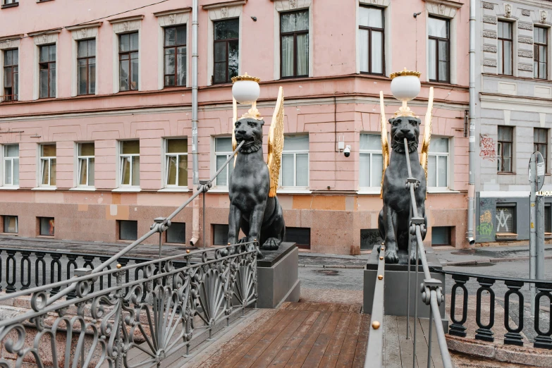 two black statues on a bridge with street lamps